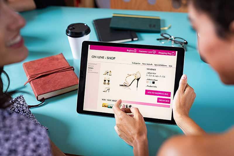 Mujeres comprando en línea un par de zapatos desde una tableta
